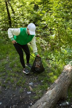 Vertical shot of a female activist collecting garbage in the woods