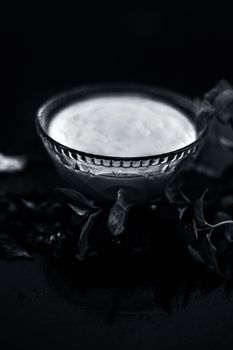 Homemade DIY face mask on the wooden surface consisting of yogurt,multani mitti or mulpani mitti (fuller's earth) and mint leaves in a glass bowl. For the treatment removal of dark patches.