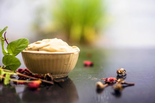 Homemade DIY face mask on the wooden surface consisting of yogurt,multani mitti or mulpani mitti (fuller's earth) and mint leaves in a glass bowl. For the treatment removal of dark patches.