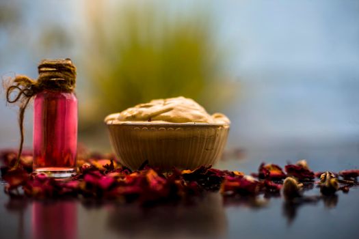 Ubtan/face mask/face pack of Multani mitti or fuller's earth on wooden surface in a glass bowl consisting of Multani mitti and rose water for the remedy or treatment of oily skin.On wooden surface.;