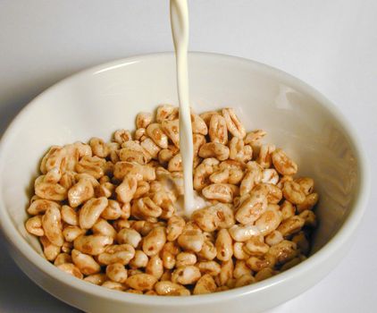 Pouring milk into a bowl of commercial breakfast cereal for a healthy start to the day