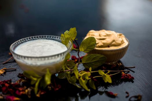 Homemade DIY face mask on the wooden surface consisting of yogurt,multani mitti or mulpani mitti (fuller's earth) and mint leaves in a glass bowl. For the treatment removal of dark patches.