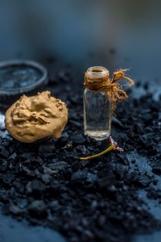 Activated charcoal face mask consisting of bentonite clay or fuller's earth or multani mitti or mulpani mitti well mixed with baking soda and coconut oil. On a wooden surface with entire constituents.