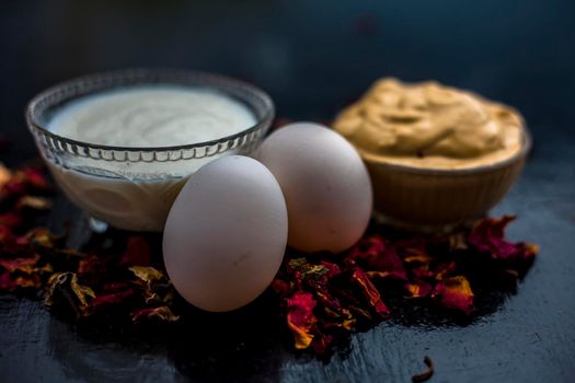 Best DIY face mask of multani mitti or mulpani mitti along with egg white and some yogurt well mixed in a glass bowl on the black wooden surface for the remedy of even skin.