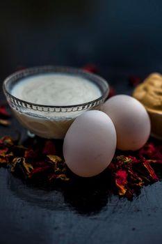 Best DIY face mask of multani mitti or mulpani mitti along with egg white and some yogurt well mixed in a glass bowl on the black wooden surface for the remedy of even skin.