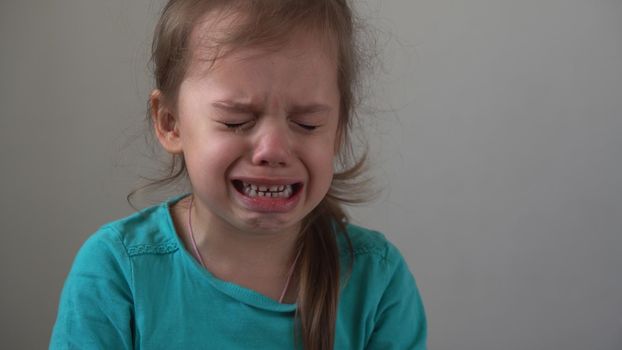 Portrait little girl sad upset child burst into tears cries sob looking at camera indoors. sincere children emotions feelings at home crying kid with pretty face. Concept childhood insult offend grief.