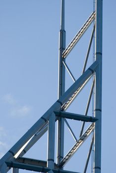 Top of a metal open frame building spire in a concept of modern architecture and design against a blue sky