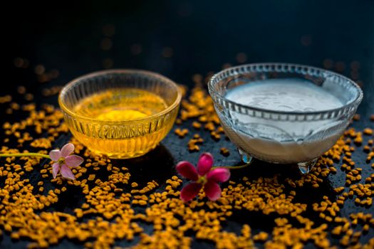 A famous natural method for dandruff on wooden surface in a glass bowl consisting of fenugreek seeds powder well-mixed with curd in a glass bowl.Along with raw curd and fenugreek seeds on the surface.