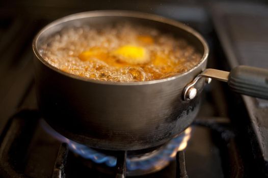 Pot or saucepan with pumpkin or butternut boiling on a gas hob with frothing bubbles and steam