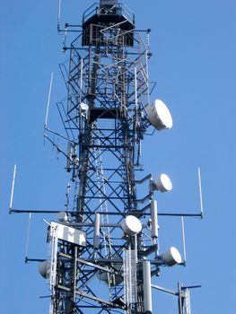 Low angle view of a steel lattice communications tower with an array of dishes for transmission and reception