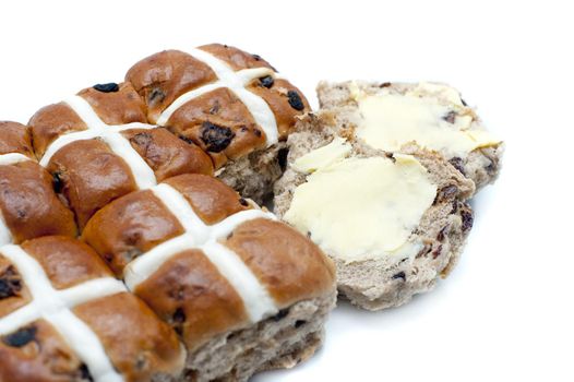 Batch of spicy Easter Hot Cross Buns with one sliced and buttered ready to eat