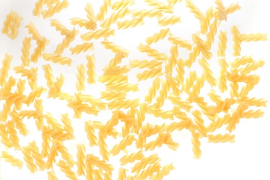 Scattered dried fusilli pasta with its distinctive spiral shape for use in traditional Italian cuisine on a white background