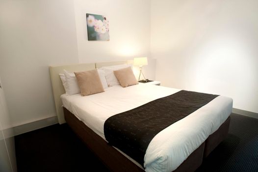 Contemporary bedroom interior with a comfortable double bed and minimalist decor in neutral colours with black accents