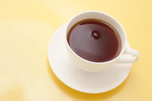 Freshly brewed cup of hot black tea for a relaxing tea break viewed high angle on a yellow background with copyspace