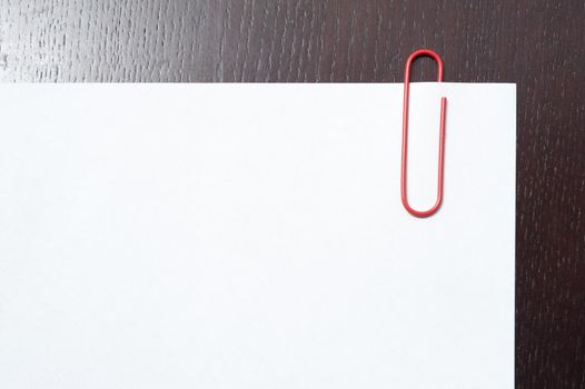 Paperclip on a blank white document with a wooden textured border on two sides