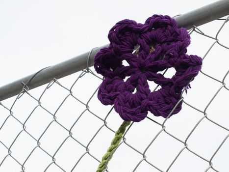 Construction fence covered with crocheted garden creatures like bugs and flowers by the Ladies Fancywork Society. Construction site of the Union Station in Denver, Colorado.