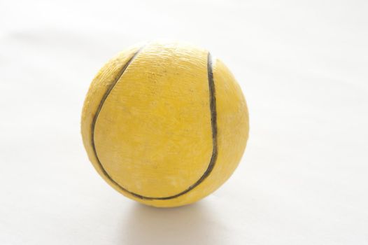 Used yellow rubber tennis ball for playing on a court backlit on a white background, close up view
