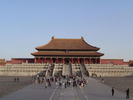 Landscape view of the exterior facade of a temple in the Forbidden City, Beijing, China with groups of people in the foreground in a travel and tourism concept