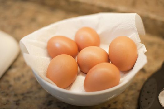 Delicious brown fresh free range farm eggs nestling in paper in a bowl waiting to be used as a cooking ingredient or for a tasty breakfast