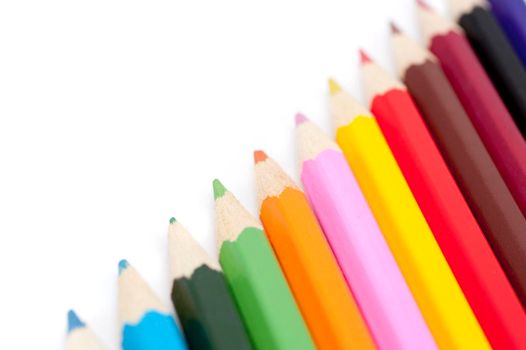 Sharpened wooden coloured pencils in a diagonal line in the colours of the spectrum for teaching art and drawing to children