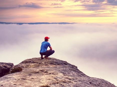 Hiker on sharp cliff of sandstone rock in rock empires park observe misty and foggy spring valley