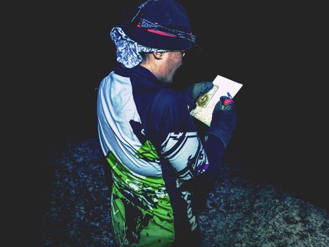 Winter night extreme runner control map.  January 25th 2019, Novy Bor, Czech Republic. Girl in forest reading map and checking a control point. Selective focus