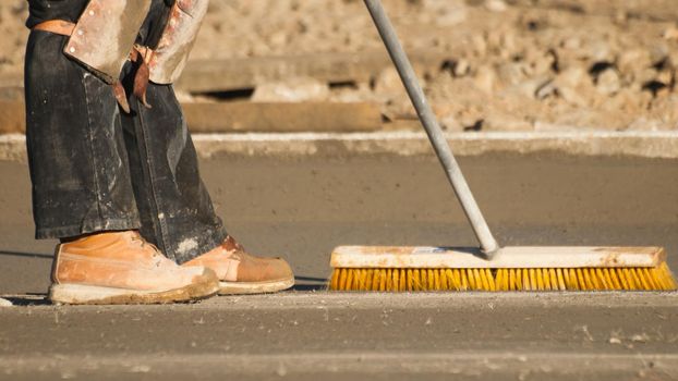 Construction worker leveling a new cement road.