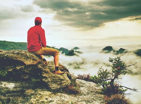 Man observe fall daybreak on peak of rock empire. Dreamy foggy landscape spring orange pink misty sunrise in a beautiful valley of Saxony Switzerland park.