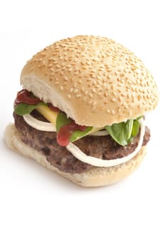 Homemade hamburger or cheeseburger on a fresh sesame bun with a thick juicy beef patty, ketchup, salad trimmings and a slice of cheese