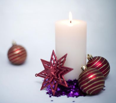 a still life of a lit christmas candle and decorations on a bright light background