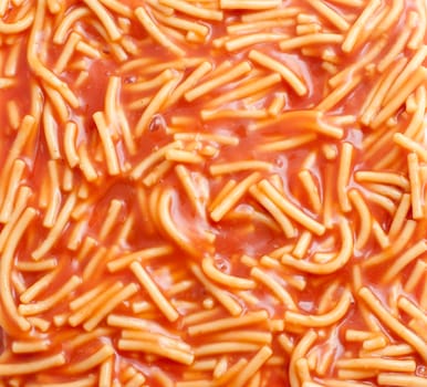 Background of canned spaghetti or noodles in tomato sauce, a quick snack and a favourite of children