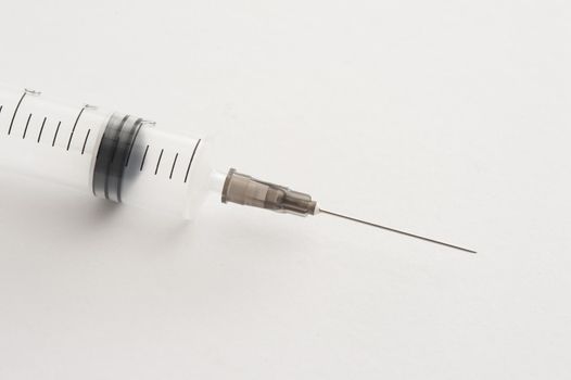 Close up of empty syringe and needle over white background with light set down shadow