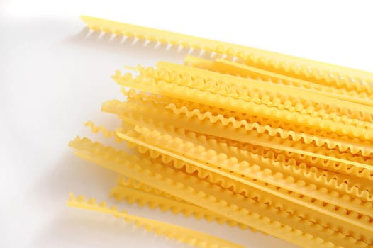 Uncooked noodles lying on white background. Daylight