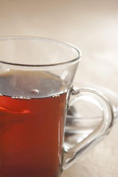 Close up partial view of a clear glass mug with a handle full of strong fresh hot black tea