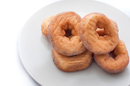 Four freshly baked sugared ring doughnuts served on a plate for breakfast or a coffee break