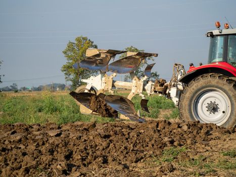 farmer with tractor plowing the land in the countryside.