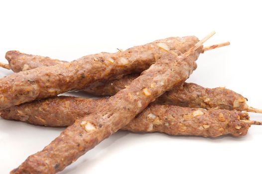 Four grilled spicy kofta kebabs made from highly seasoned minced lamb served on a plate, close up view