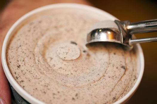 Serving up tasty creamy cookie ice cream from a bowl using a stainless steel scoop, close up high angle view