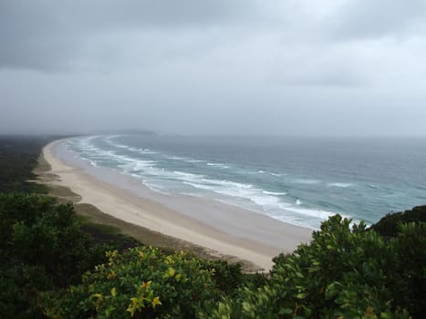 rain clouds and waves blown onto the coast  and a sandy beach
