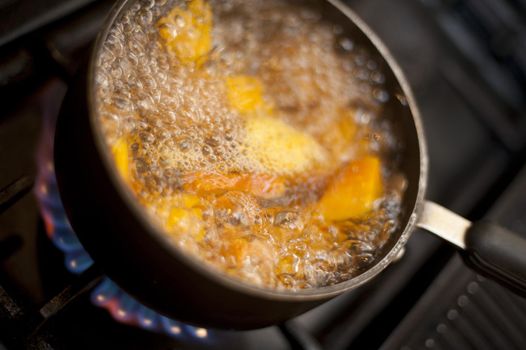 Boiling pumpkin in a pot of water on a gas hob, high angle view