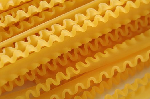 Background Close Up of Frilled Edges of Dry Lasagna Noodles - Arranged in Diagonal Pattern Across Frame