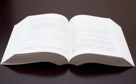 A studio shot of an open paperback book over a black background