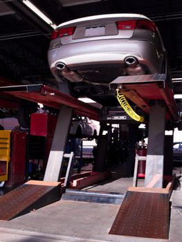 Car on a lift getting repaired in auto repair shop.