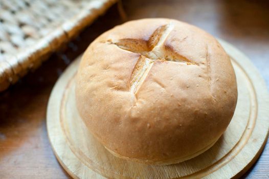 Freshly baked traditional round crusty cob roll on a board to eat as an accompaniment to a meal , close up high angle view