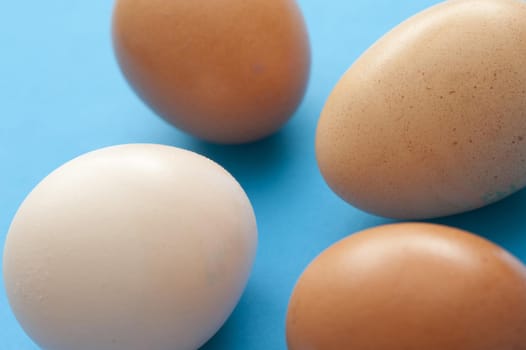 Four healthy raw brown and white eggs on a blue background for use as an ingredient in cooking and baking or for a delicious breakfast