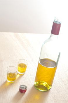 Close up Unlabled Bottle and Glasses of Yellow Wine on Top of a Wooden Table