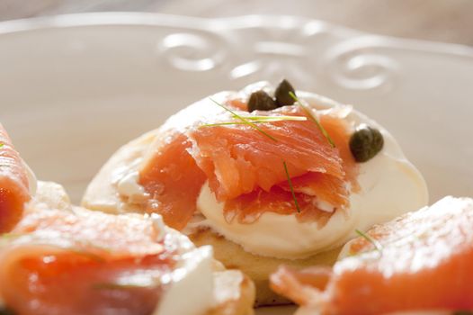 Delicious snacks or appetizers of fresh smoked salmon and capers on cream cheese served on sliced bread