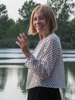 female pensioner having fun and smoking a cigarette in a park - aging free and wellness concept