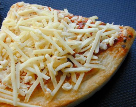 Slice of uncooked Italian pizza with a pastry base topped with tomato paste and grated cheese