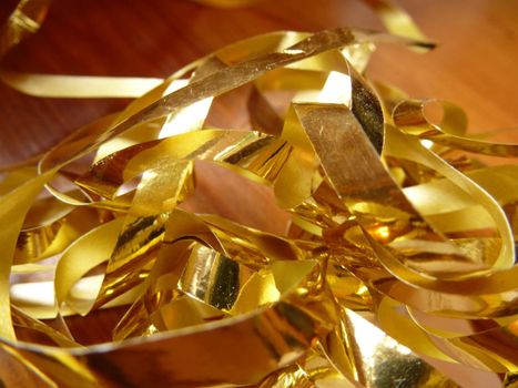 Close up Tangled Gold Foil Cuttings on Top of Wooden Table